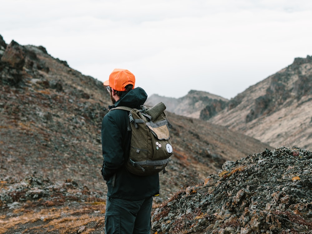 Mann steht mit Rucksack auf grauem Berg