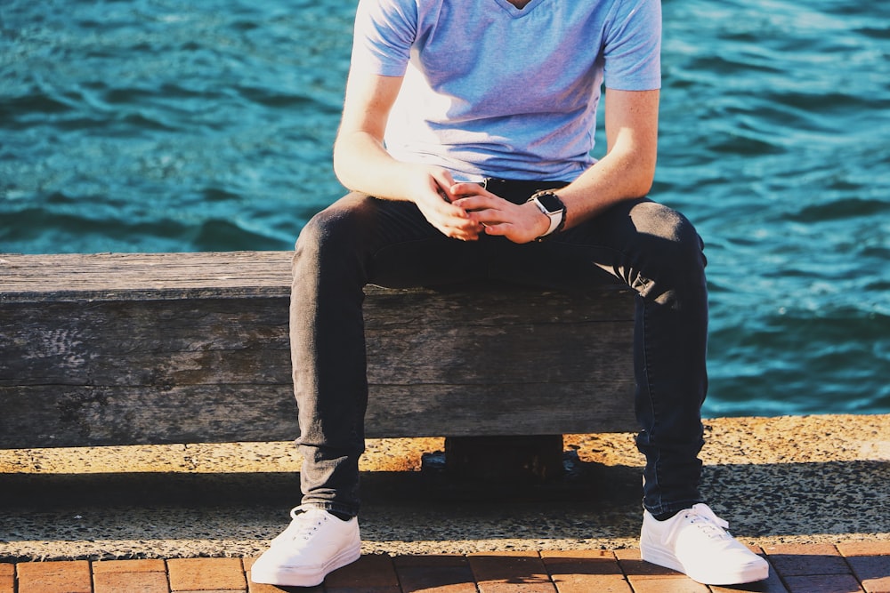 man in gray V-neck shirt sitting on bench