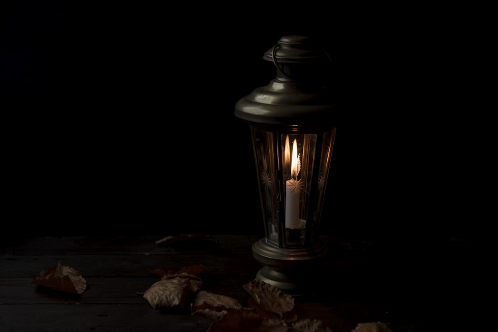 lighted lantern with dried leaves beside it