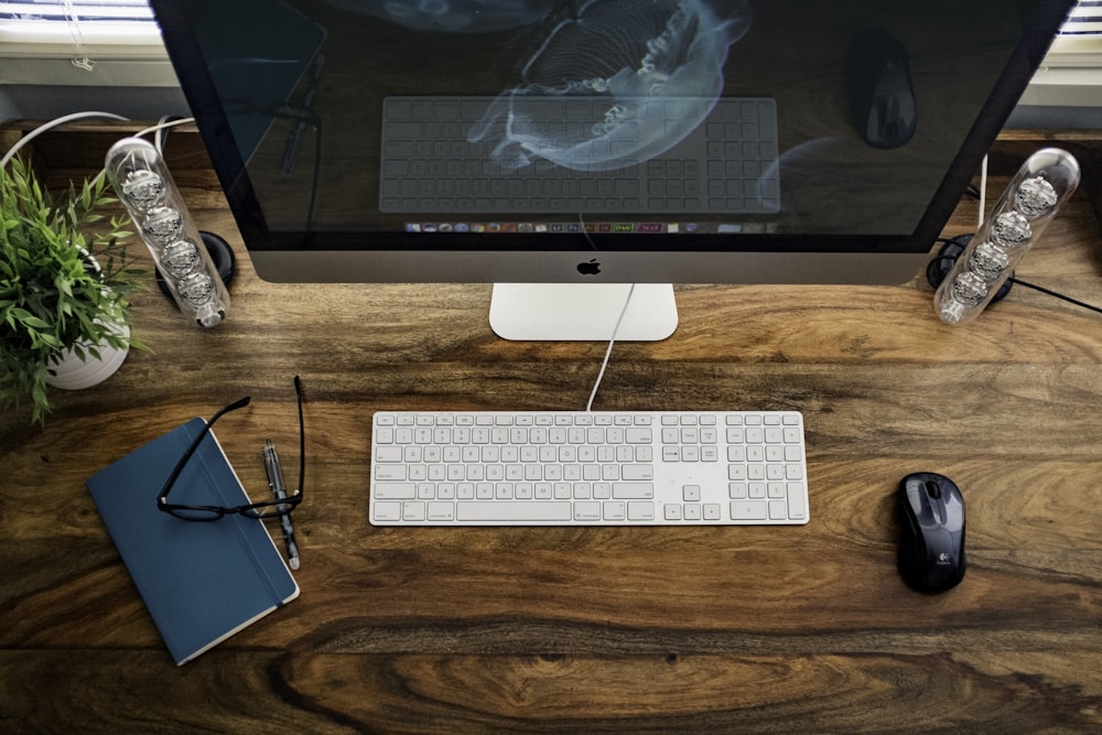 silver iMac near keyboard, mouse, and eyeglasses