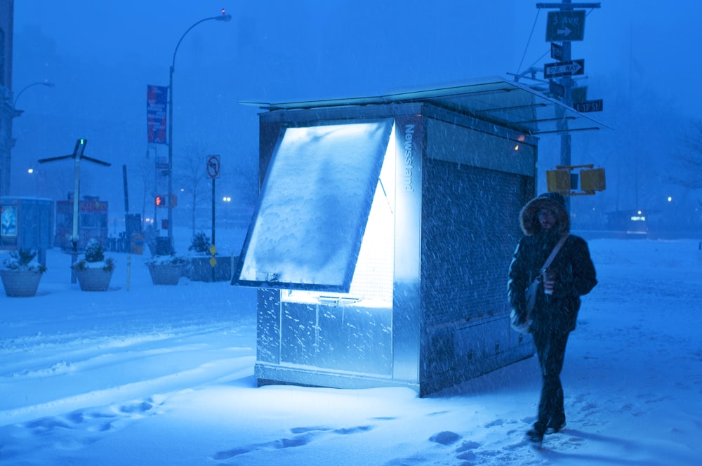 uomo che cammina sulla neve in giacca marrone