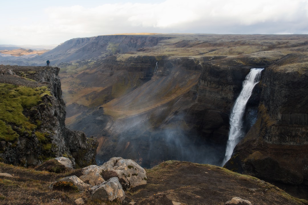 waterfalls on mountain under gray sky,