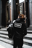 person wearing hoodie and standing beside the building