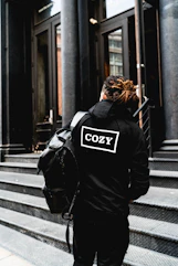 person wearing hoodie and standing beside the building