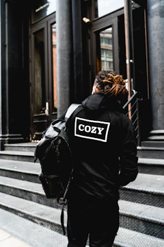 person wearing hoodie and standing beside the building