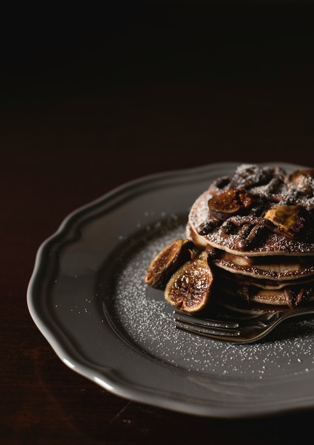 shallow focus photography of pan cakes with slices of banana and syrup on top on gray plate