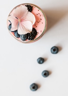 pink beverage on glass with blackberries and pink flower on top