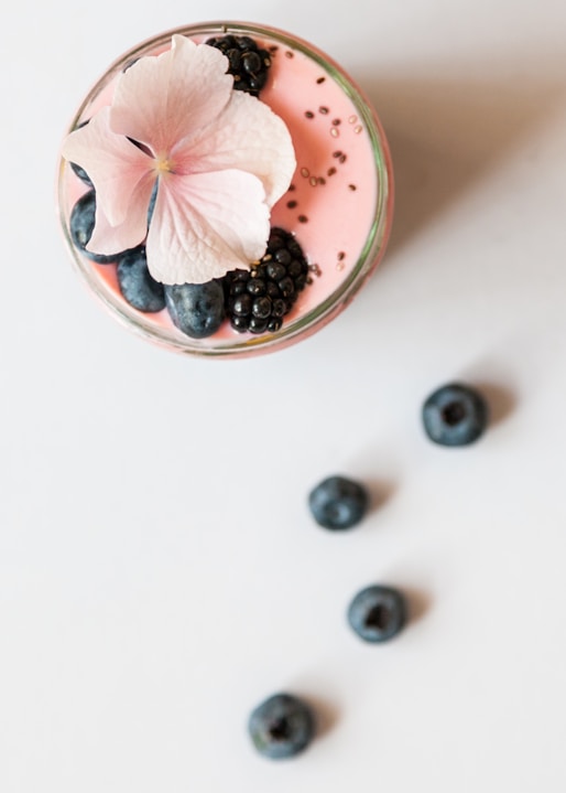 pink beverage on glass with blackberries and pink flower on top