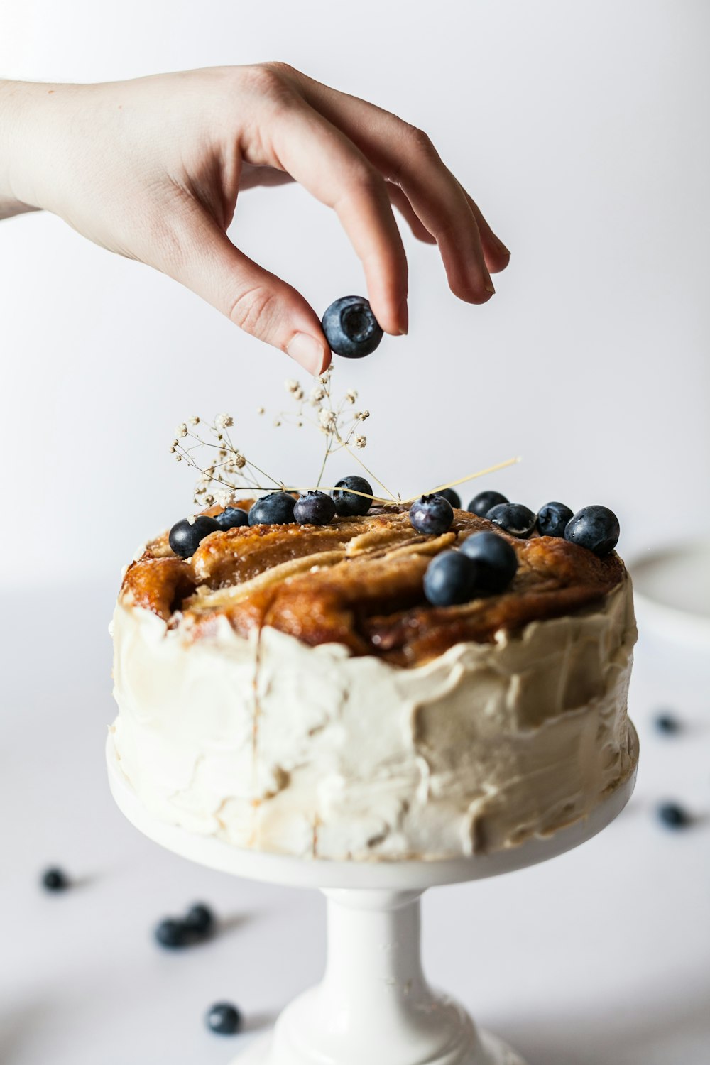 person holding black fruit near cake