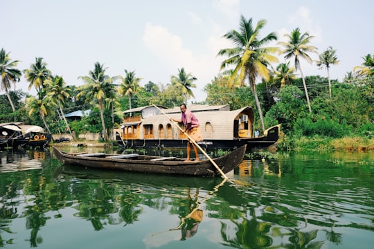 man riding on boat during daytime in Kerala Backwaters India