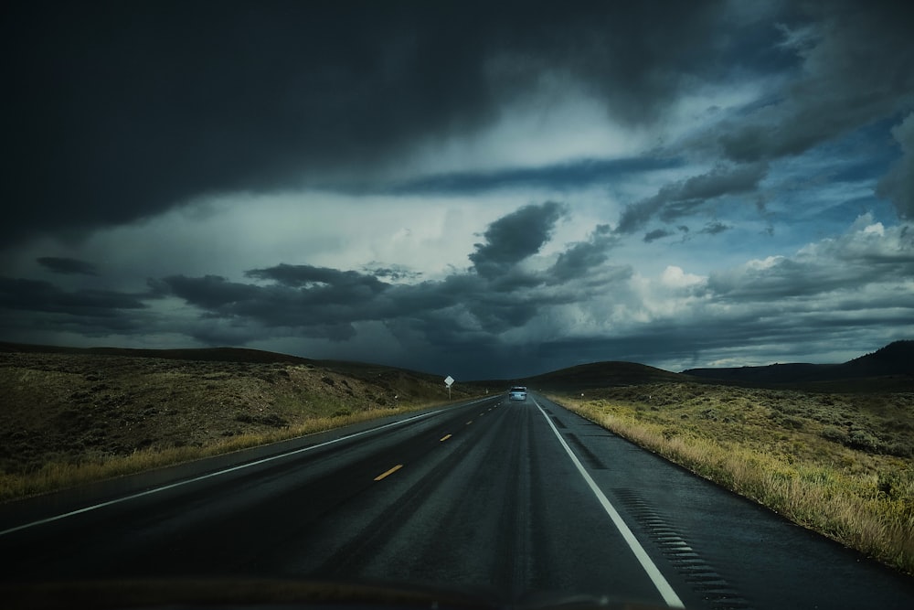 Asphaltstraße in der Nähe des Feldes unter weißen Wolken