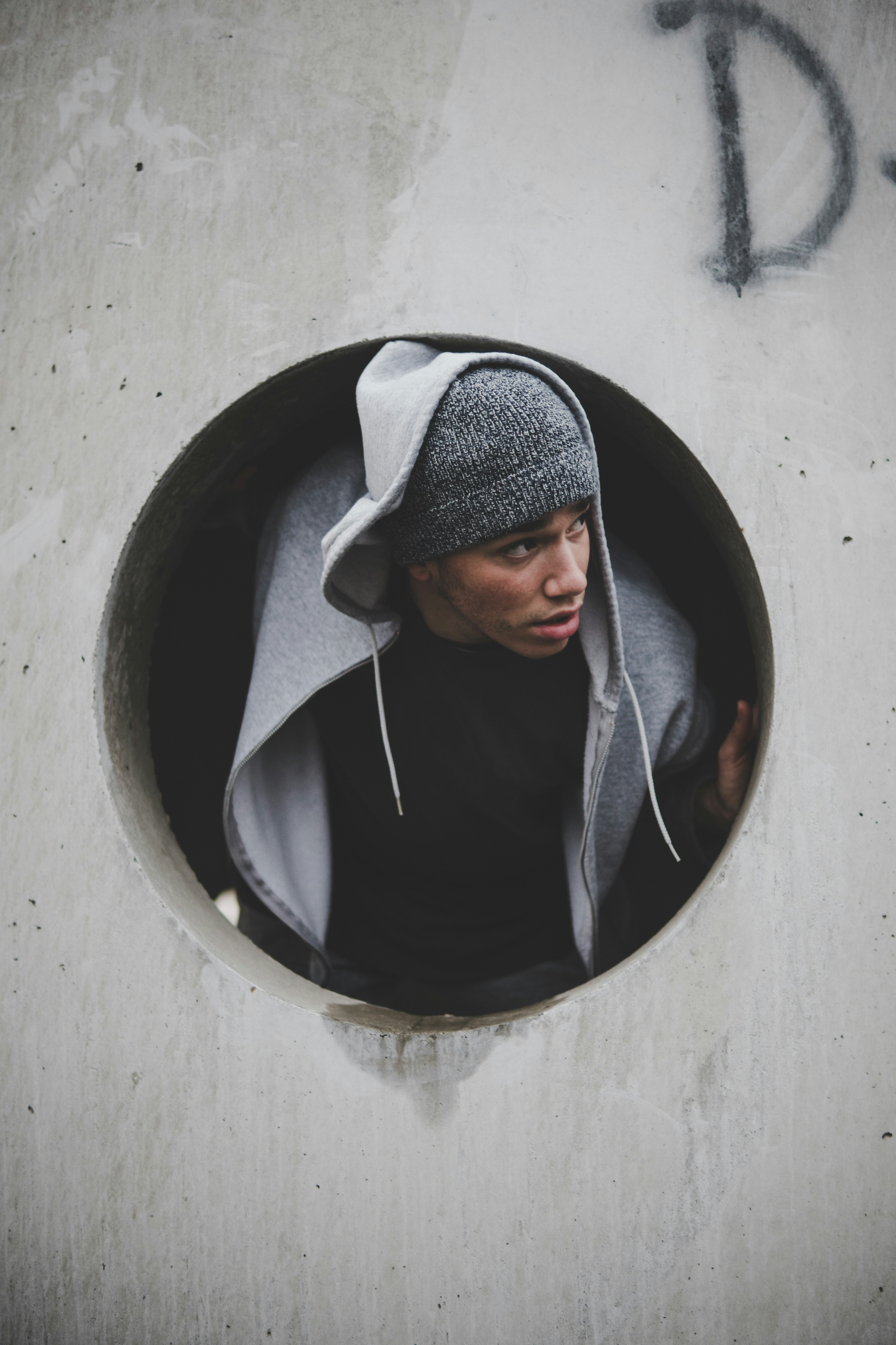 great photo recipe,how to photograph holy; man wearing black shirt and knit cap with hoodie jacket inside concrete hole