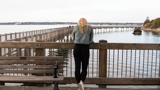 woman in gray jacket and black pants standing on brown wooden dock during daytime in Fairhaven United States