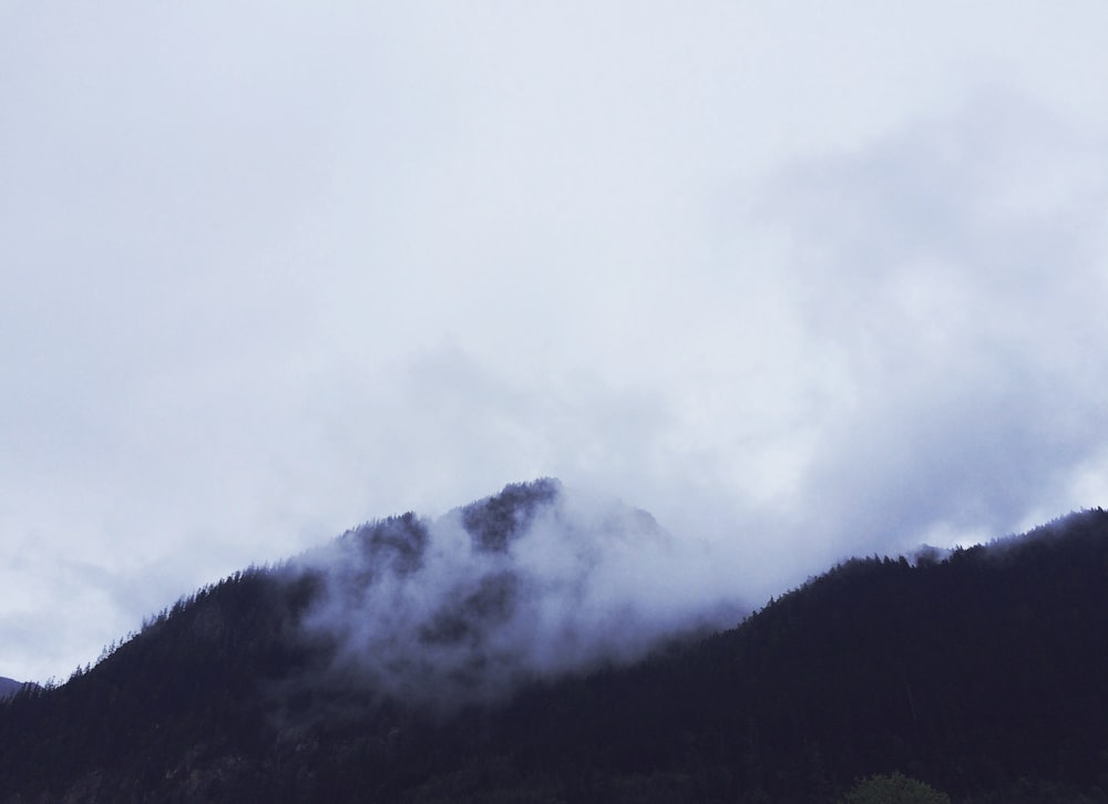 Photographie de vue aérienne de la montagne sous les nuages blancs