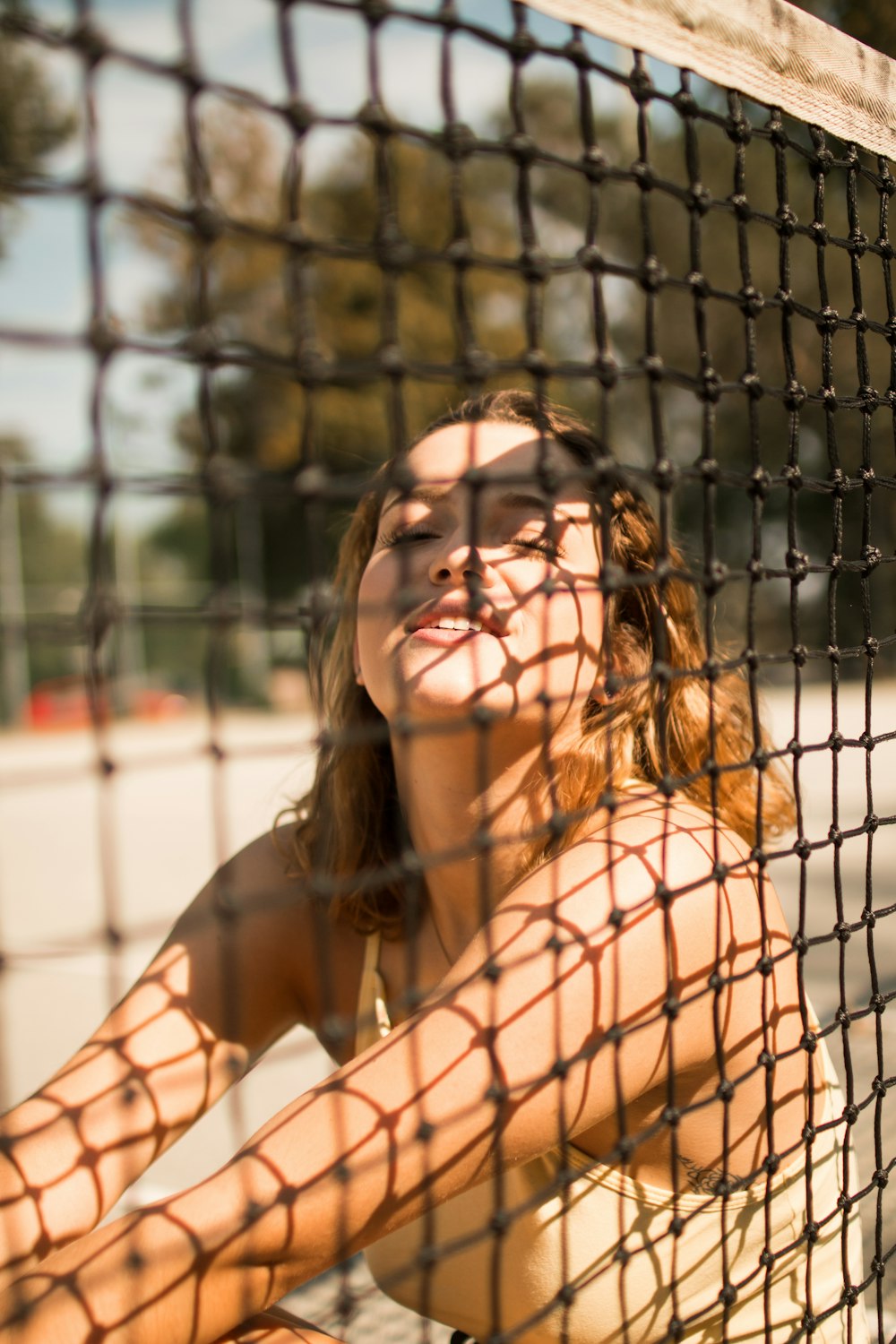 woman sitting beside sports net during daytime
