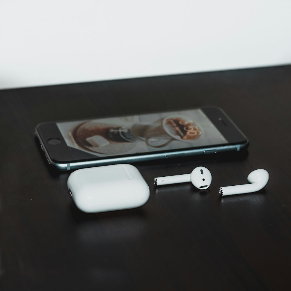 iPhone 6 gris sidéral et Apple AirPods avec étui sur table en bois noir