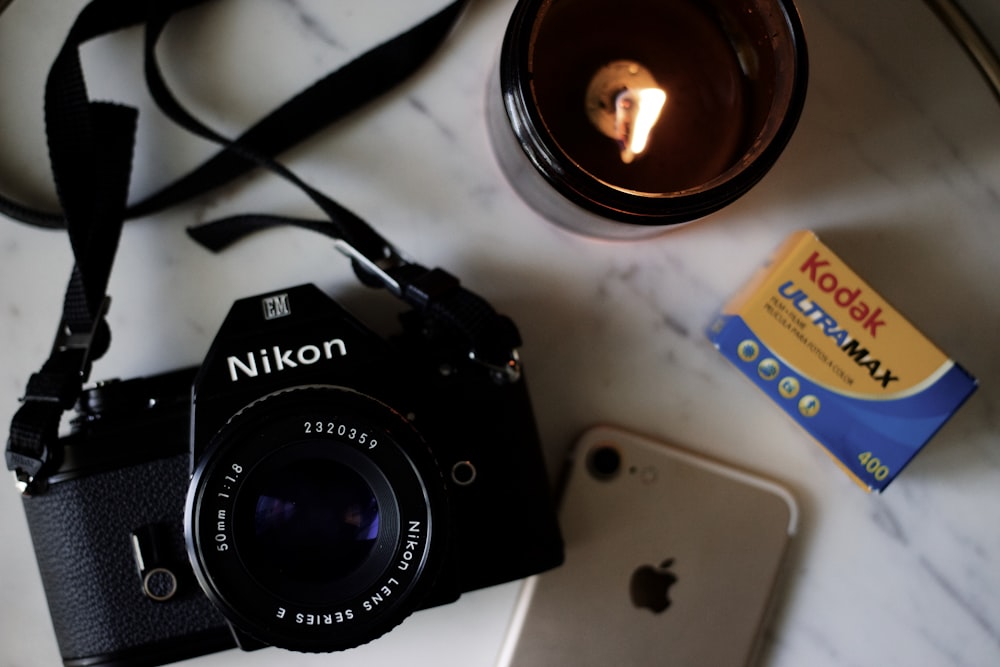 cámara DSLR Nikon negra sobre mesa blanca