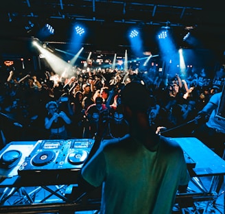 man performing DJ music with crowd during nighttime