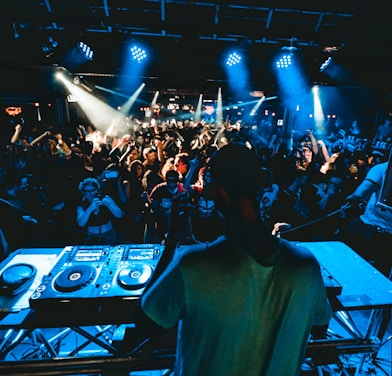 man performing DJ music with crowd during nighttime