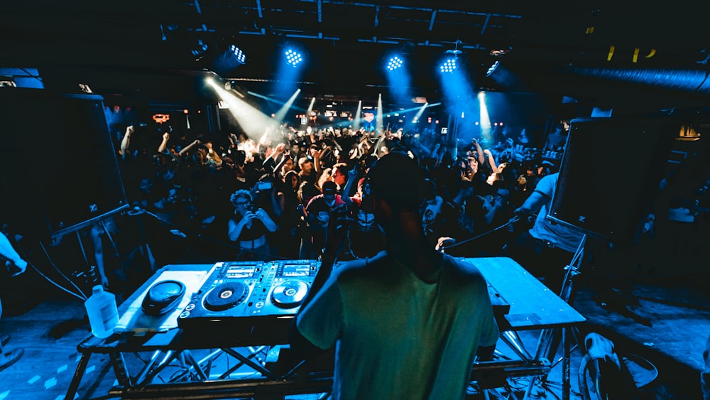 man performing DJ music with crowd during nighttime