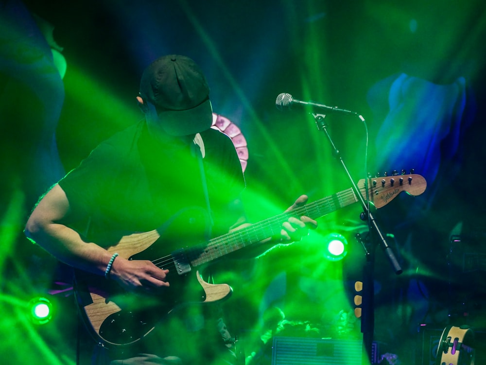 man playing electric guitar in front of microphone