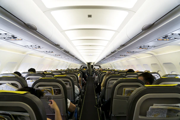 A bustling commercial airplane cabin filled with happy travelers settling in.