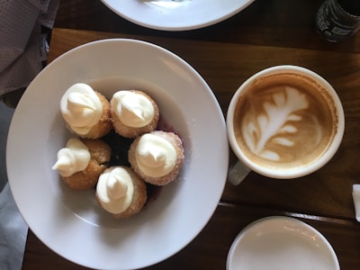 Close-up of a coffee cup and a plate with traditional German pastries on a wooden table.
