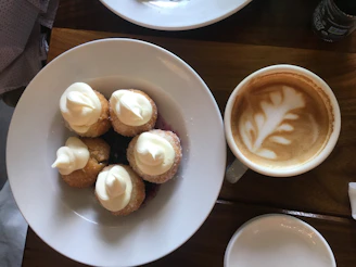 A group of friends enjoying coffee and pastries around a rustic wooden table.