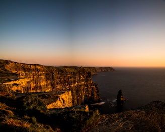 A panoramic view of Uluwatu Temple perched on a cliff during sunset.
