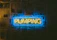 A neon sign displays the word 'PUMPING' in yellow against a blue rectangular background. The sign is mounted on a wall covered with newspaper pages.