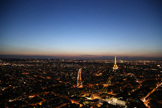 A vibrant aerial view of a bustling cityscape at sunset with glowing lights and busy streets.