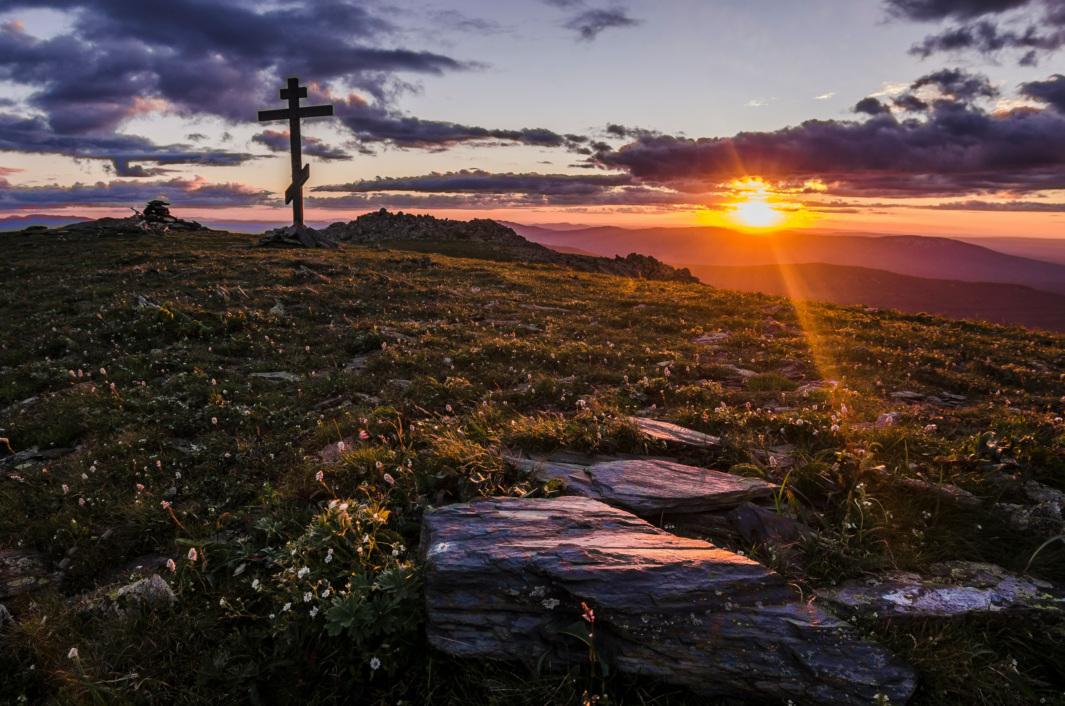 cross in an open field by the setting of sun