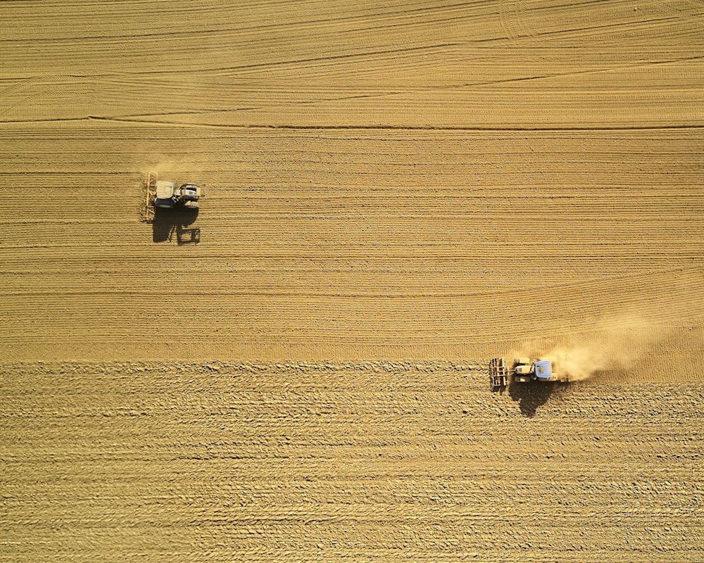 aerial view of two harvesters on brown field