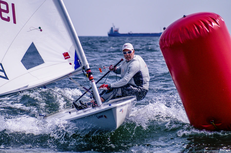 A helmsperson steering a racing dinghy close to a red mark