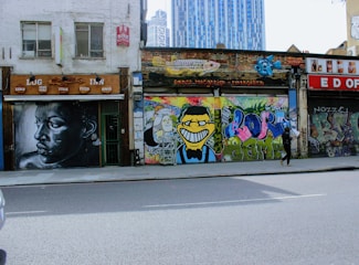 A street scene with a solitary figure walking past a vibrant mural.