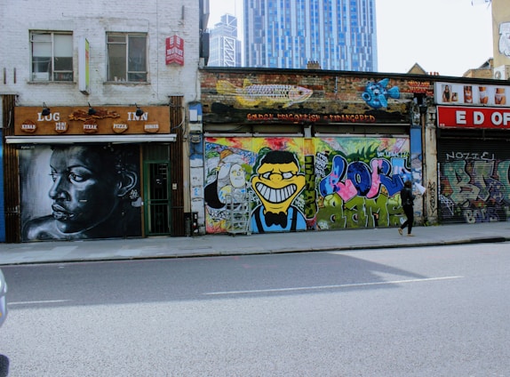 A street scene with a solitary figure walking past a vibrant mural.