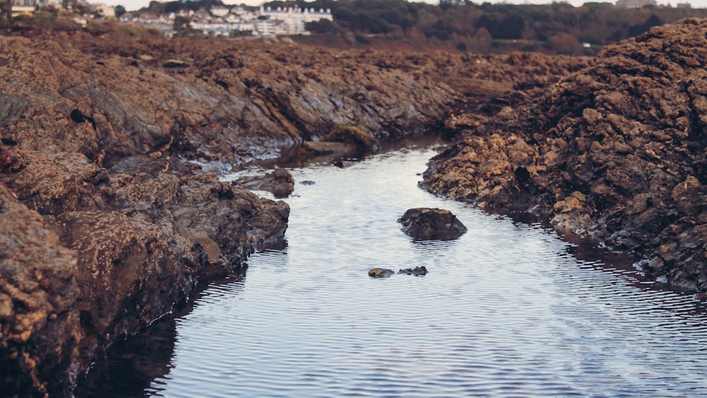 photo of body of water surrounded by rocks