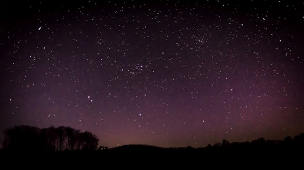 A starry night sky with glowing zodiac constellations in shades of deep blue and purple.