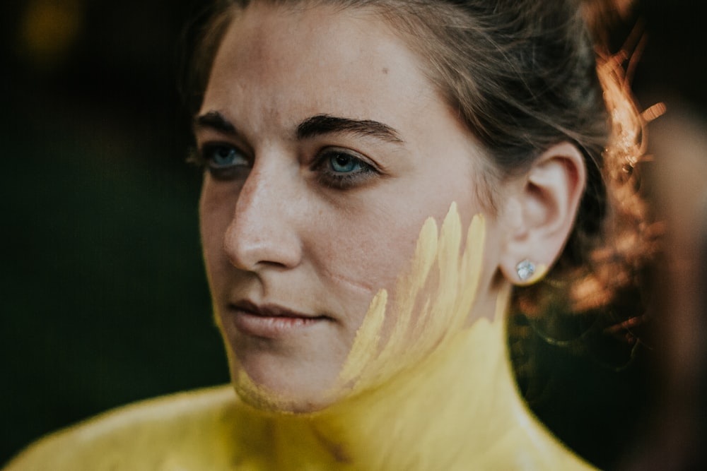 woman looking sideways with yellow paint on face