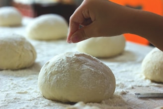 A chef’s hands preparing dough on a floured surface.