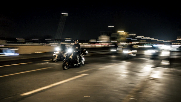Evening scene capturing bikes speeding under glowing streetlights along the high-speed stretch.