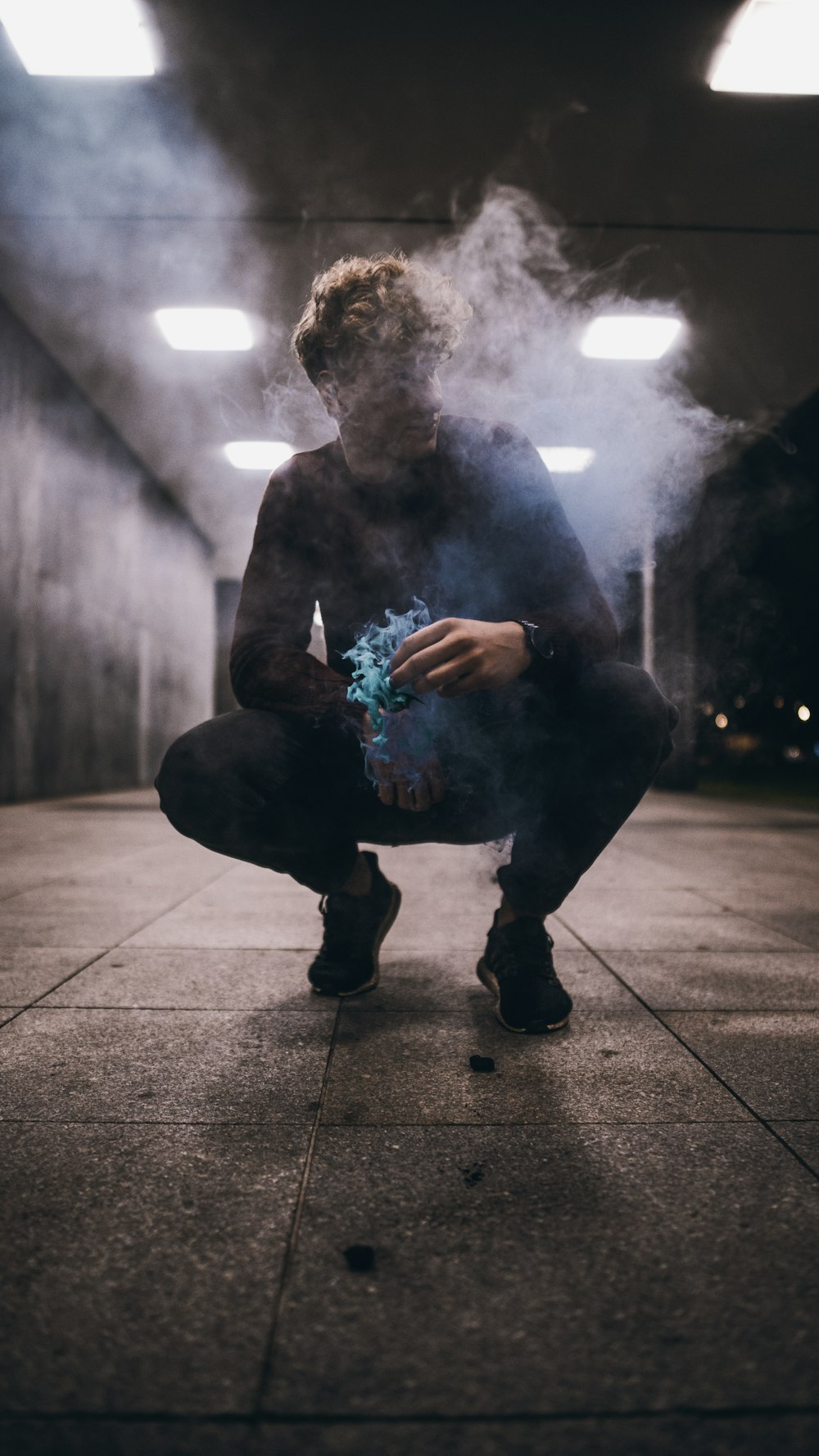 low light photography of man asian squatting on concrete pavement