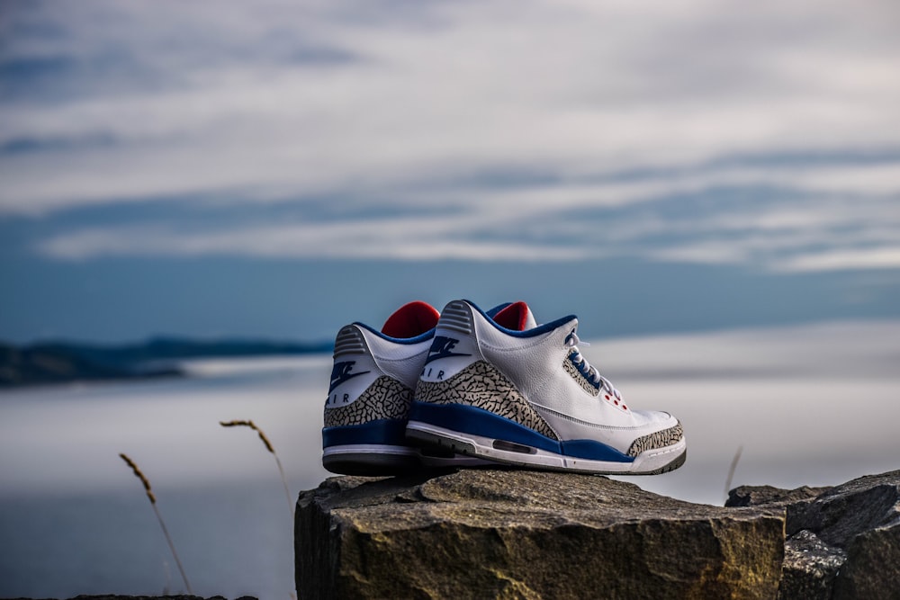 Un par de Air Jordan 2 blancos y azules en un fragmento de roca