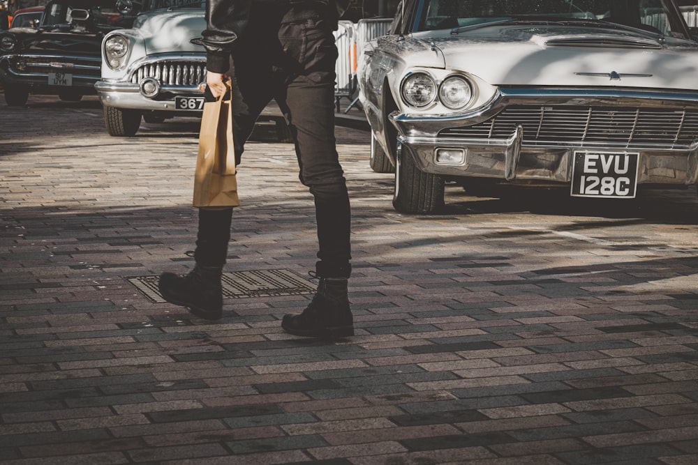 person wearing black pants and black boots walking on brown and black concrete brick floor