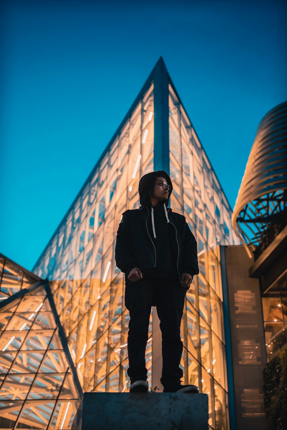 man standing front of curtain wall building at night time