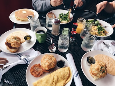 A colorful spread of classic western breakfast items including eggs, bacon, and pancakes with syrup.