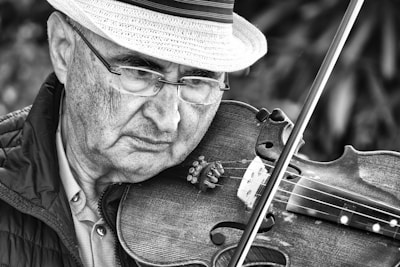 grayscale photography of man playing violin