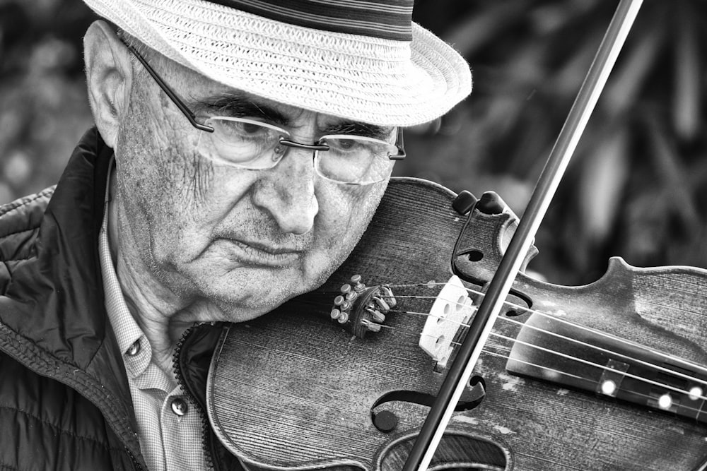 grayscale photography of man playing violin