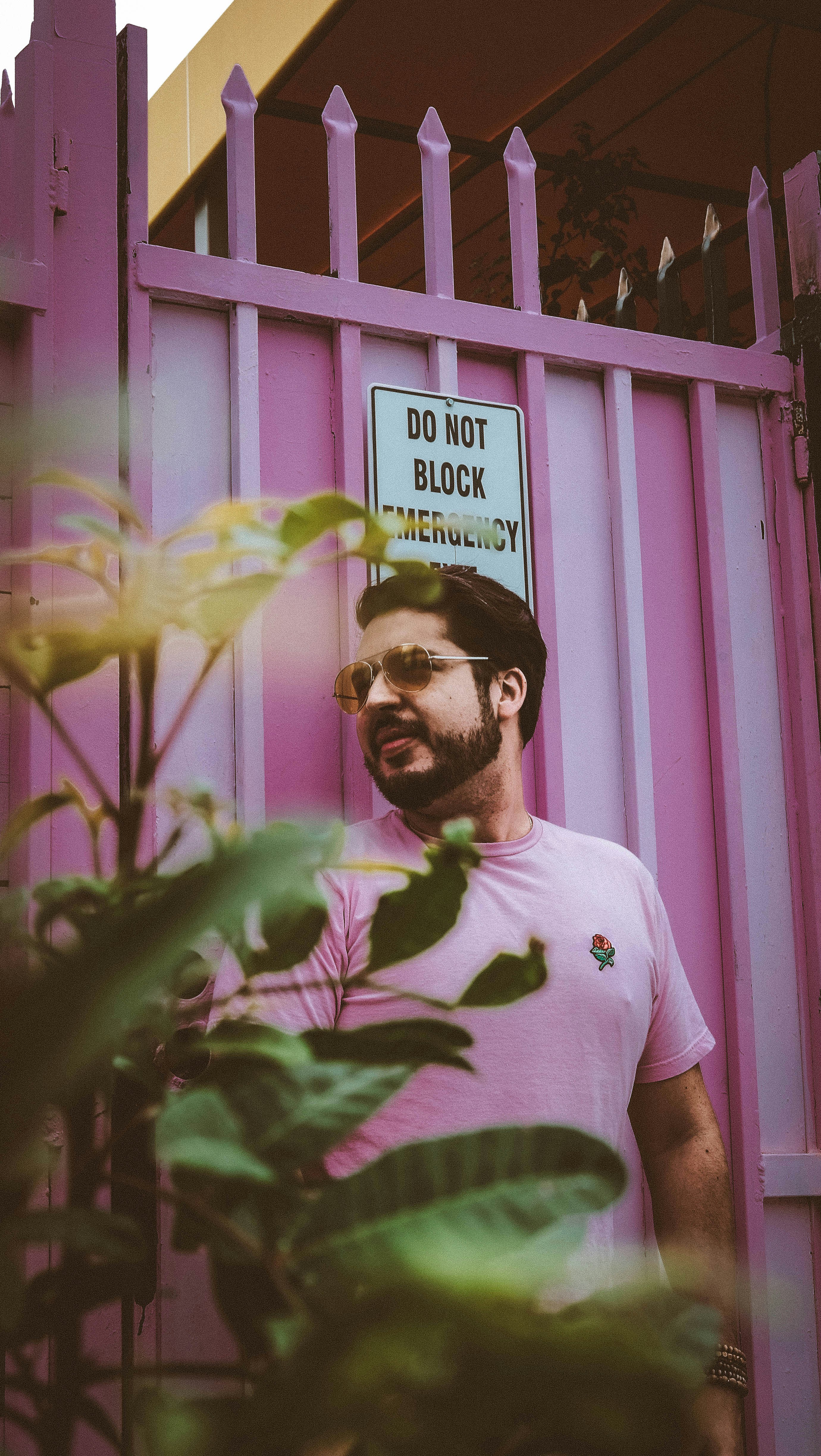 man leaning on pink gate looking sideways