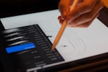 person holding stylus pointing on drawing pad